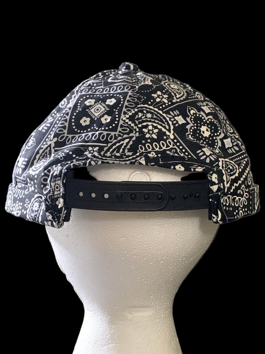 Backside of  black paisley fabric roll cap hat with black snaps 
