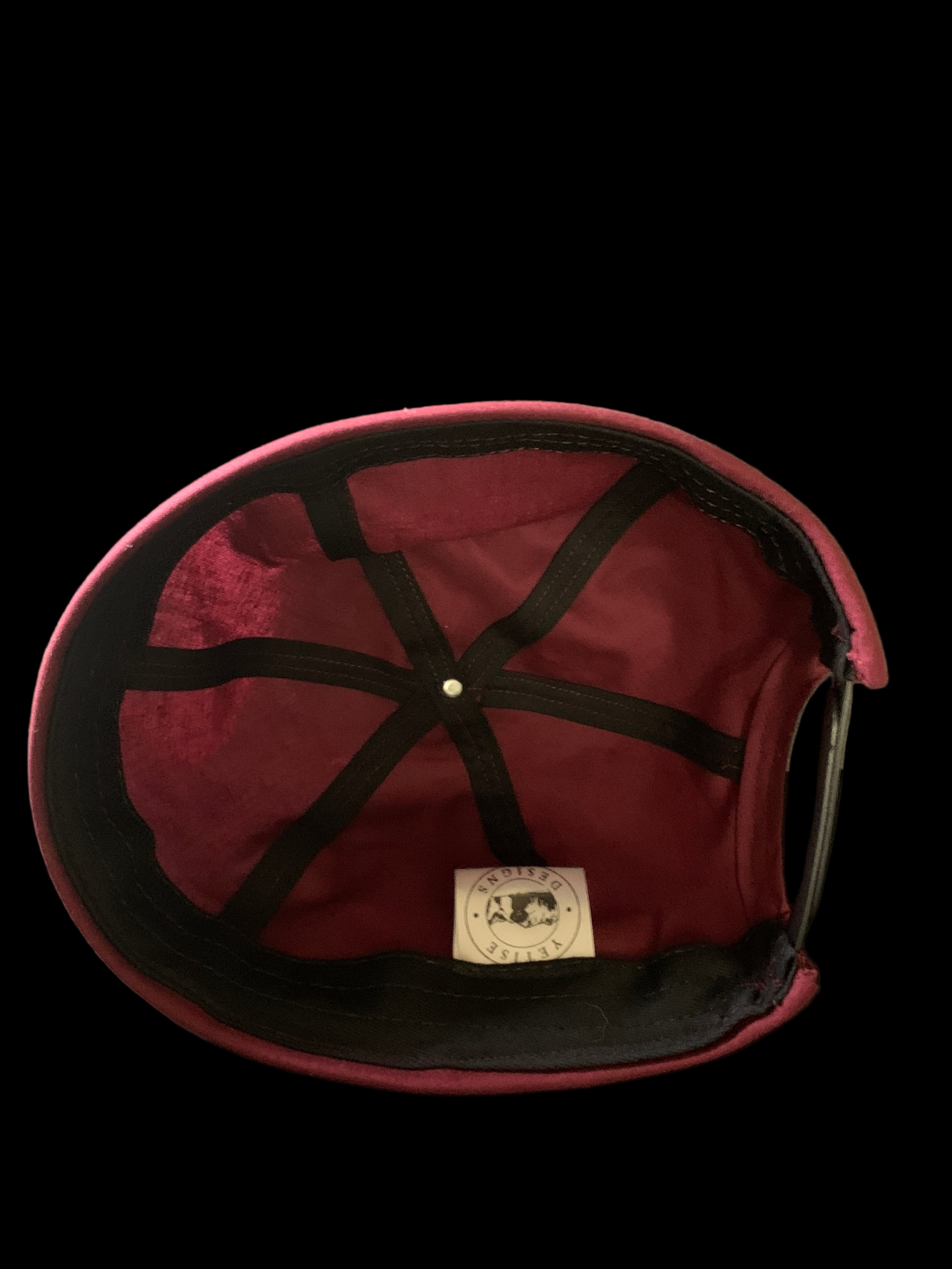 Inside view of a burgundy hat with white tag and black trimmings. 