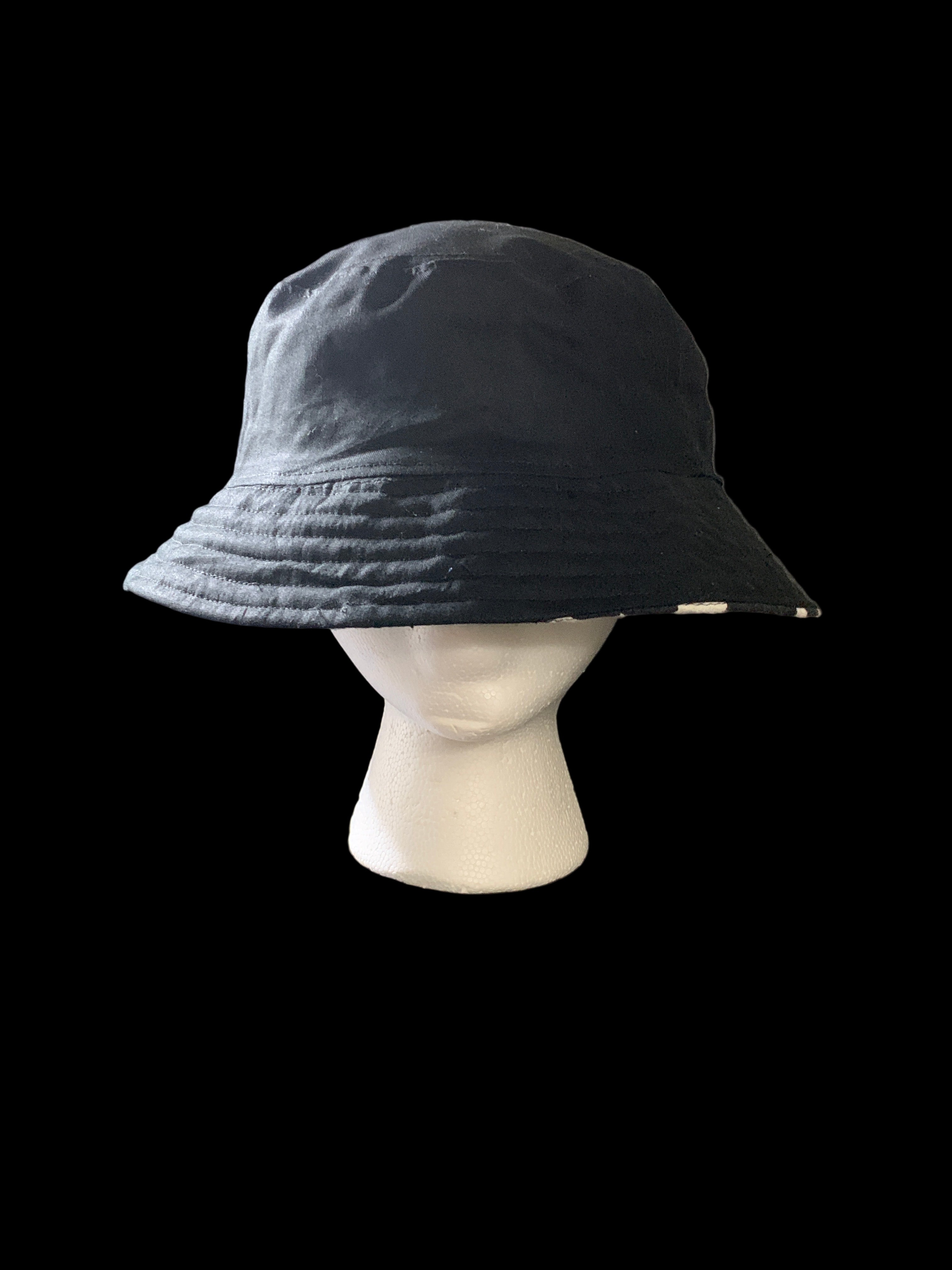 Black cap on a mannequin head against a dark background. Front  view