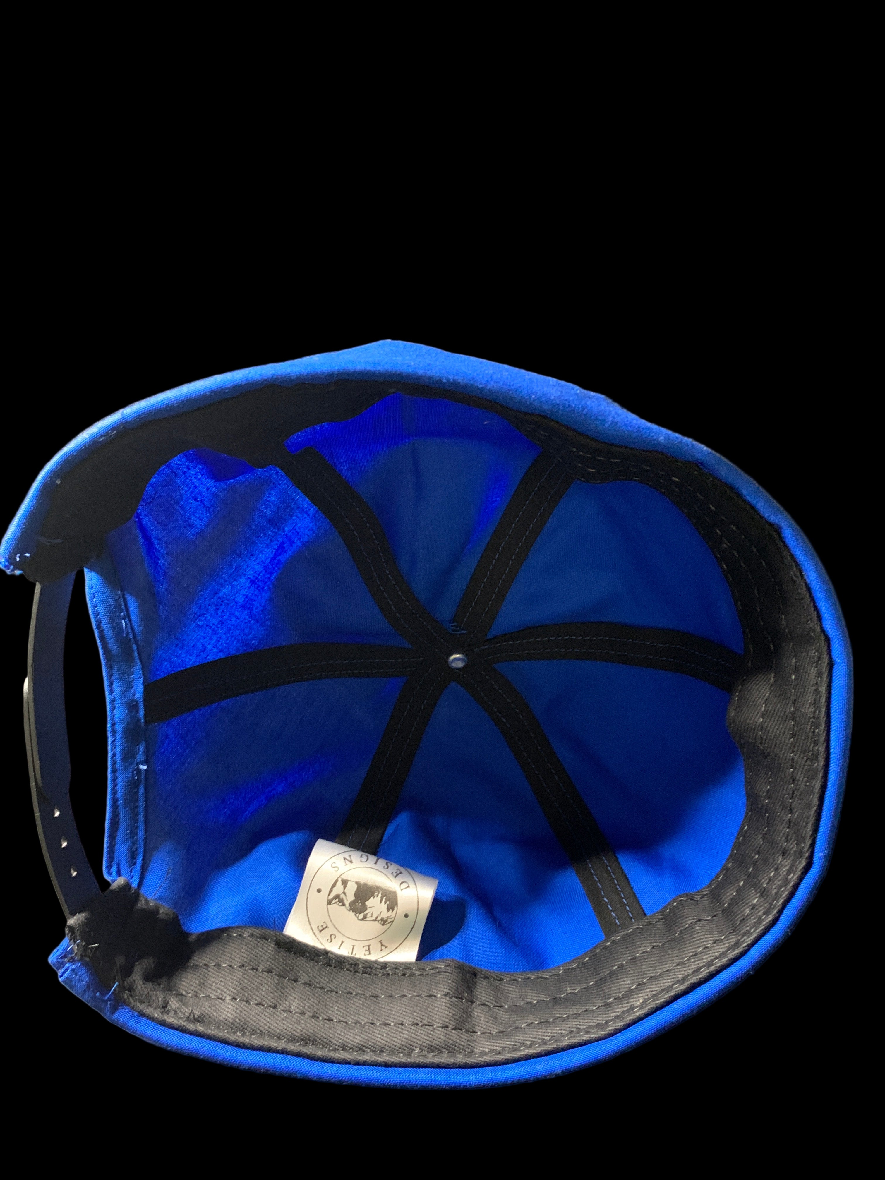 Blue cap with black straps and black trim with black background. Inside view 