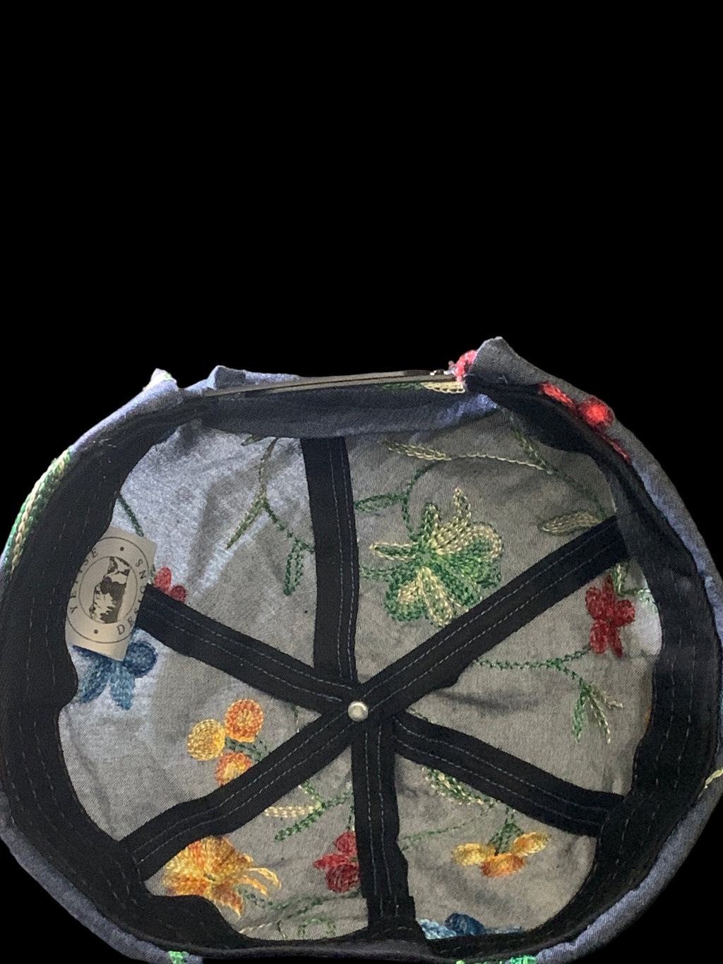 Floral embroidered hat with white tag and black trimmings. Inside view 
