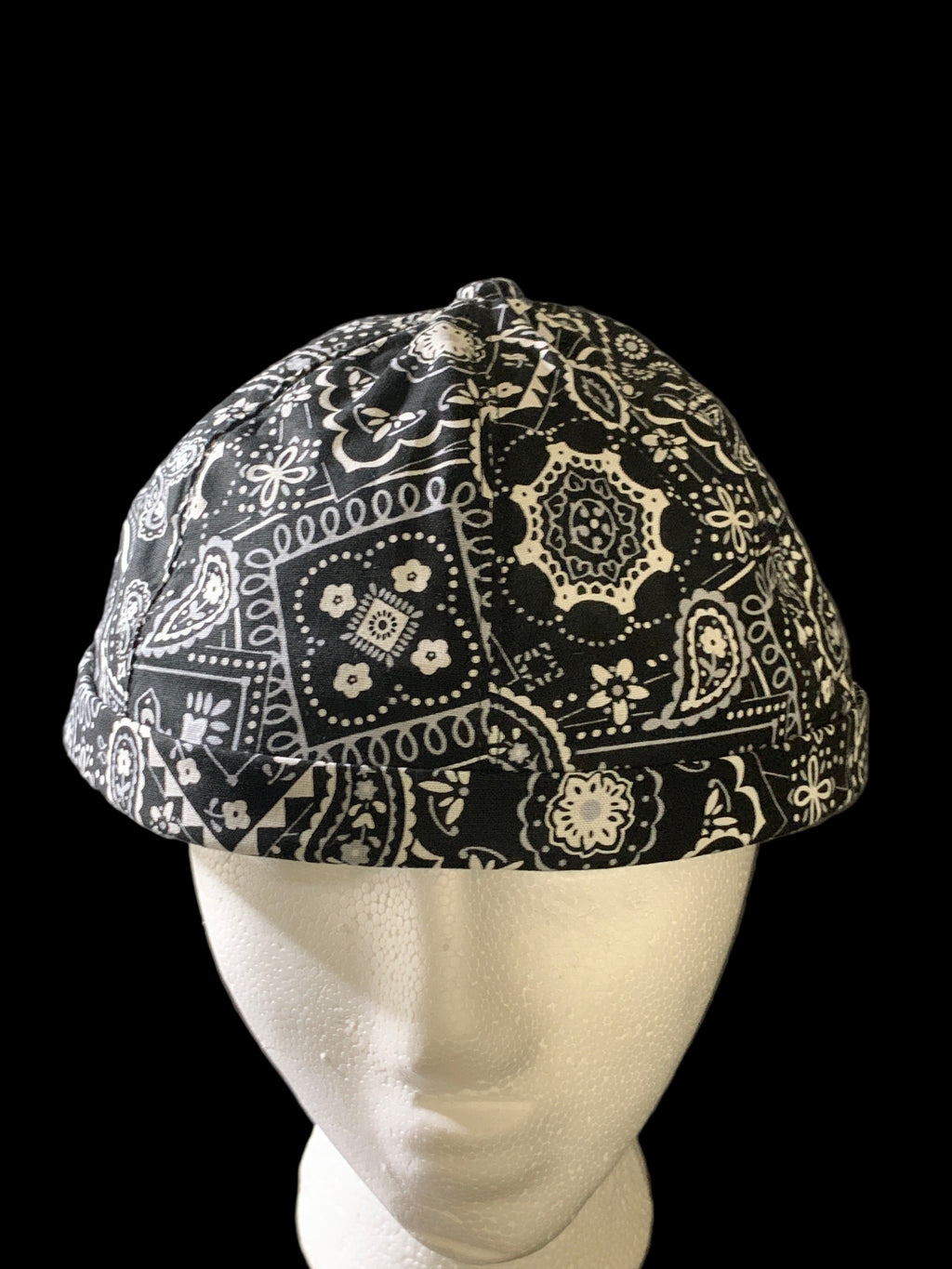 Black paisley fabric roll cap with black botton on top. Front view 