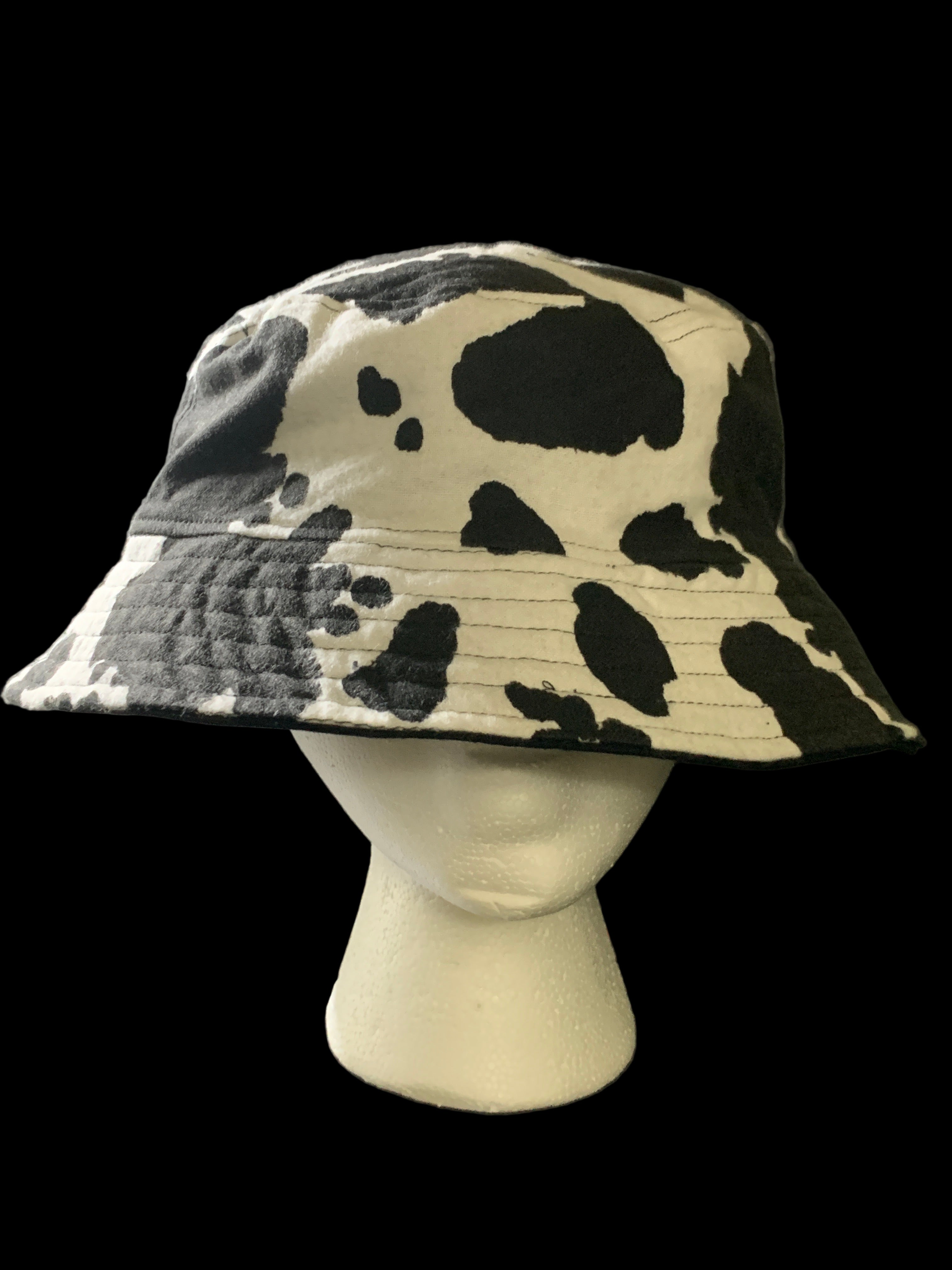 Cow print hat on a mannequin head against a dark background. Front view