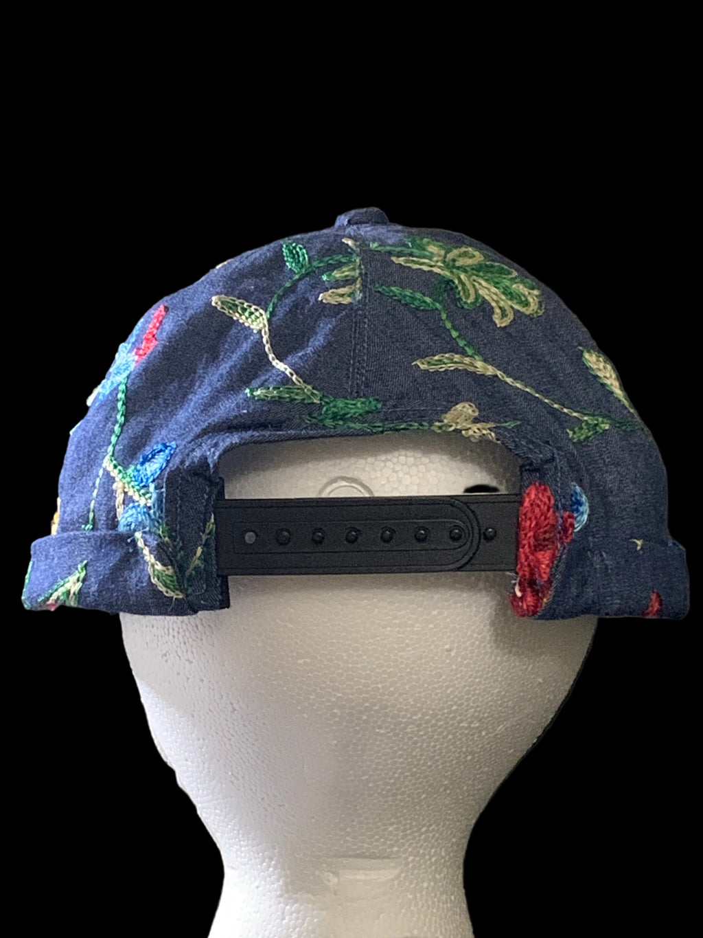 Backside view of Floral-patterned  hat with black snaps and black background. 