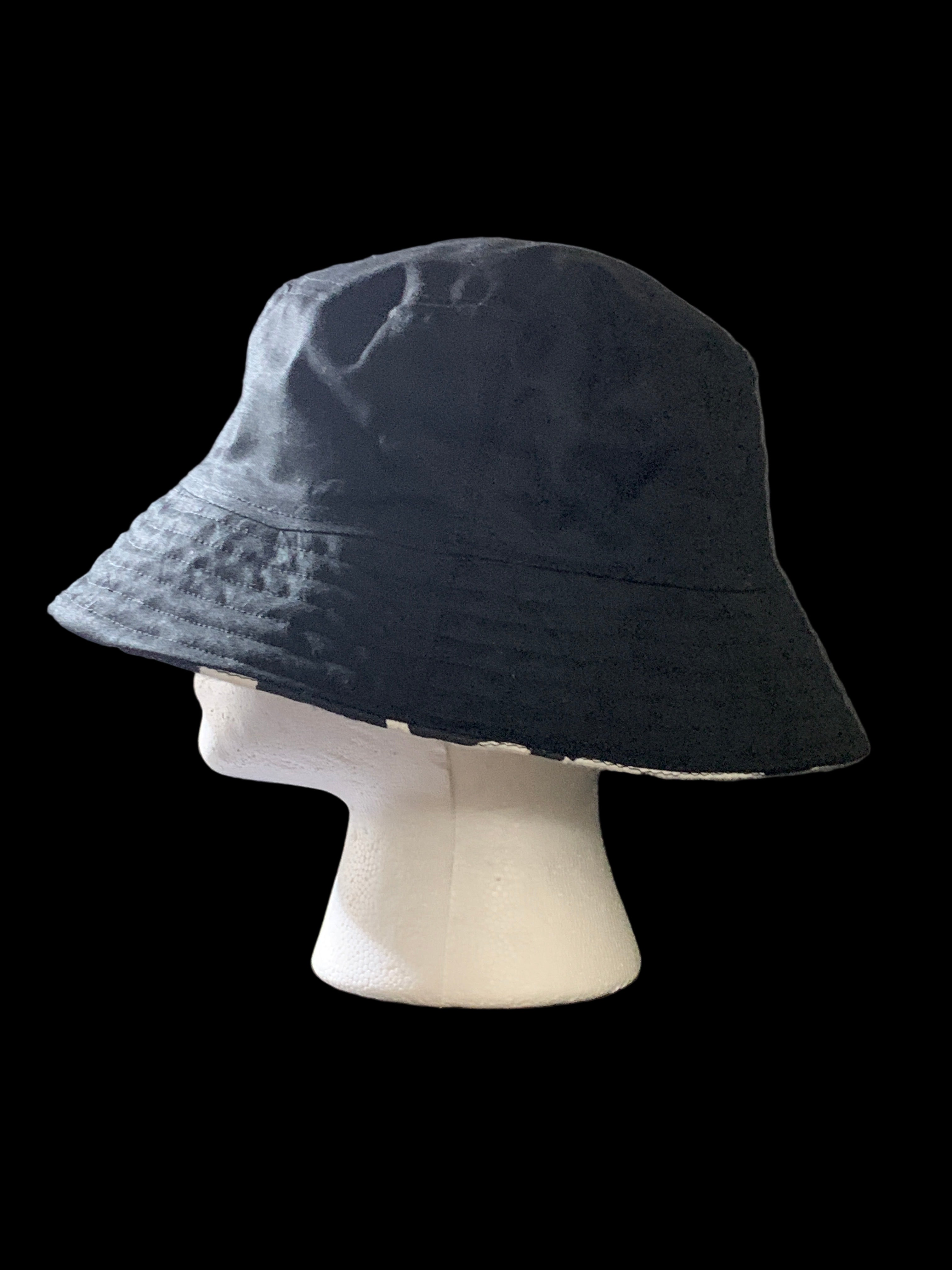 Black bucket hat on a gray surface with a white object next to it