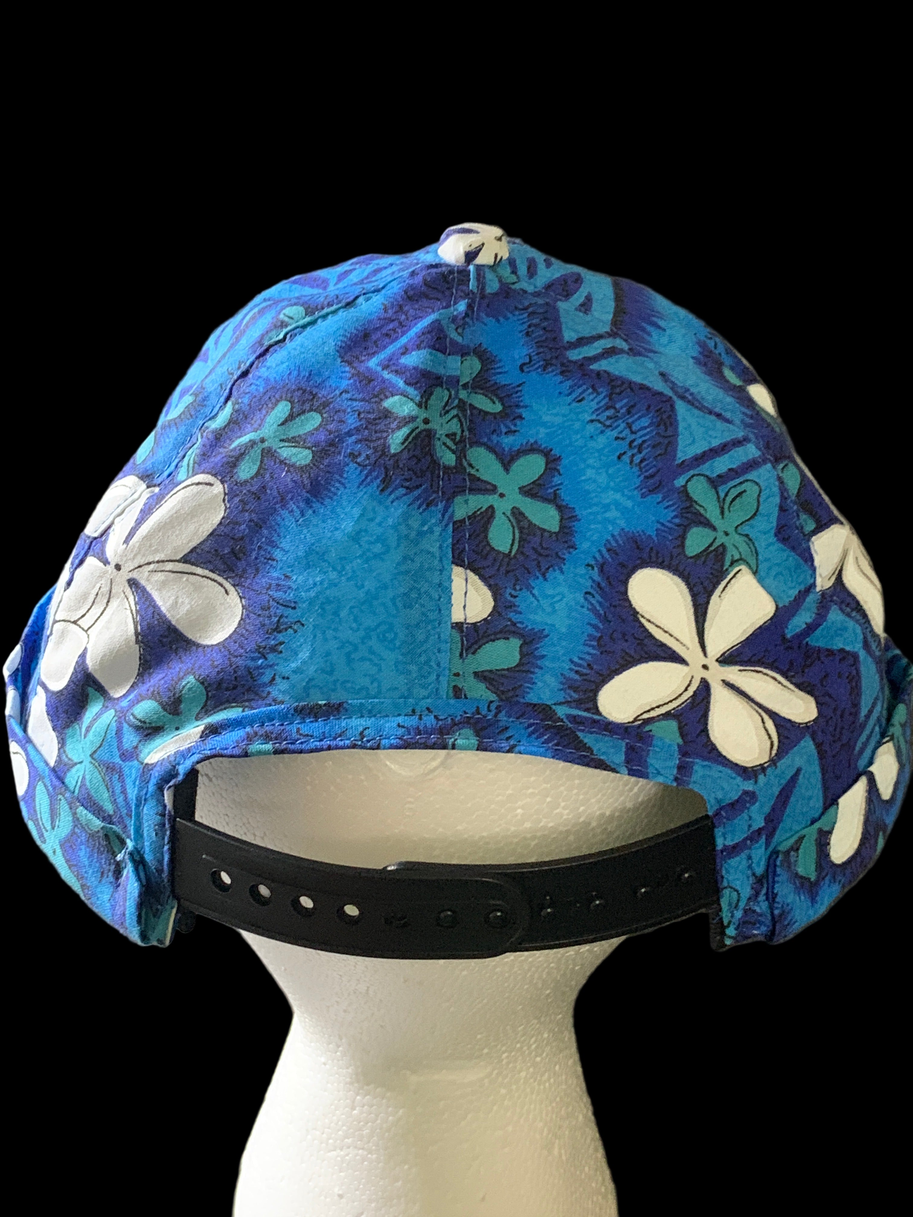  Polynesian Blue floral-patterned hat with black snaps and black background. 