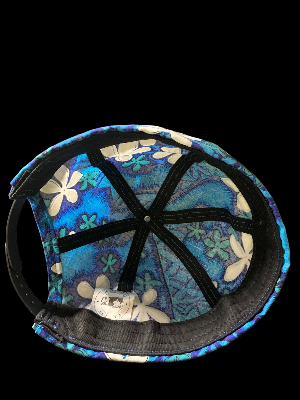 Polynesian Blue hat  with white floral pattern fabric. Inside view with white tag and black trim. 